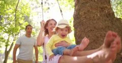 Family with a little girl swinging happily in the park