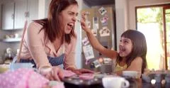 Mom and daughter having fun together in kitchen while baking