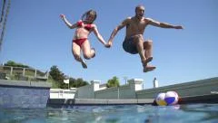 Happy Couple Jumping In Swimming Pool Together