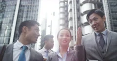 4K Portrait of young Asian business group chatting as they walk through city