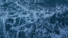 Slow motion disturbed ocean water surface by sailing boat at sunset. Slow motion