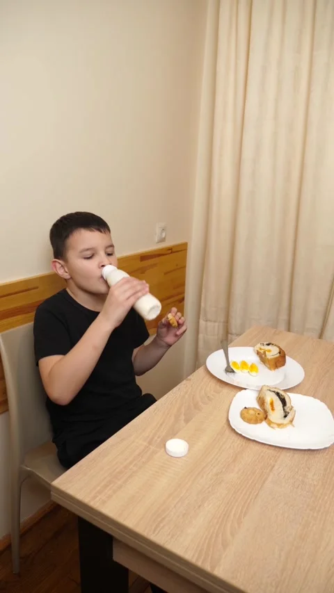 04A guy eats pastries, drinks tea and yogurt while sitting at a table. Stock Footage 313593735