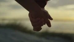 Couple holding hands at the beach in slow motion