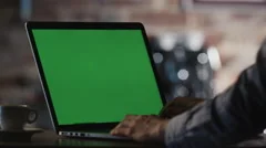 Man using Laptop with Green Screen in Cafe