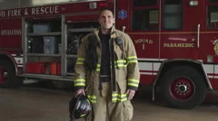 Proud fireman in uniform in front of fire engine truck