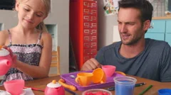 Father Having Tea Party With Daughter In Bedroom