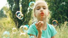 Closeup portrait girl blowing soap bubbles in the grass