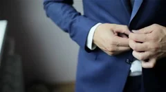 Stylish man in a suit buttoning jacket. Close up