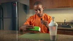 Young african american man in domestic kitchen, eating a sports proteic bar