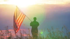 Soldier waves  American flag against   sunset sky. Slow motion scene