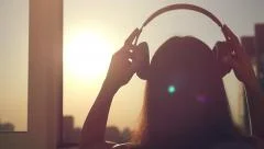 Slow motion of Young woman putting on headphones, listening to music, dancing