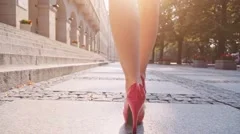 Sexy woman legs in red high heels shoes walking in the city urban street.