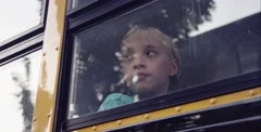 Sad young man looking out school bus window