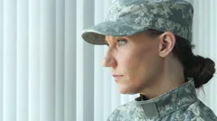 A female soldier looking out a window and then at the camera