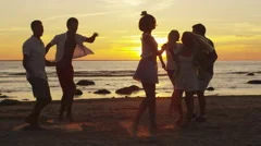 Group of Happy Young People are Dancing on the Beach in Sunset Light