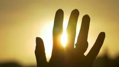 Hand in silhouette raised up to the sun