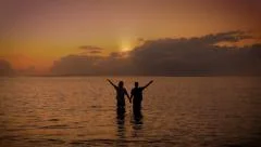Two people hold hands together and raise their arms to the sky