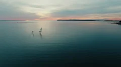 Aerial drone shot of windsurfer and paddleboarder at sunset