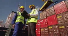 Dock workers discuss logistics at the harbor amidst shipping industry activity. 