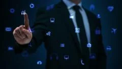 Man touching a visual screen with holographic computer icons. Blue.