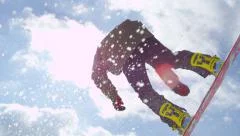 SLOW MOTION CLOSEUP: Extreme snowboarder jumping kicker in sunny winter