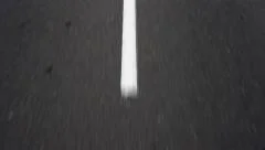 Car moving on the road, passing over broken white marking lines.