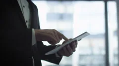 Close-up of a businessman in a suit using a tablet next to a big window