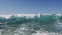 Large wave crashes on rocky shore in slow motion
