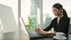 Young asian business woman working with her laptop in modern office. Dolly shot.