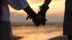 lesbians holding hands at sunset on the beach