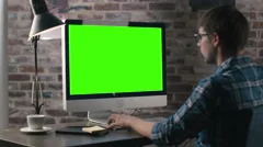 Young man is working on a computer with a mock-up green screen