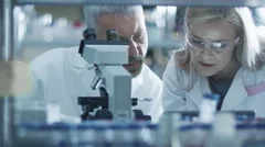 Male and female scientist are working with a microscope and a tablet in a lab