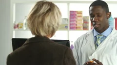 Male pharmacist consulting with female customer about prescription drugs