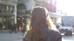 Girl with headphones walks in city