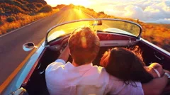 Happy Couple Driving on Country Road into the Sunset in Classic Vintage Sport