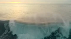 aerial drone view of ocean wave breaking at sunset