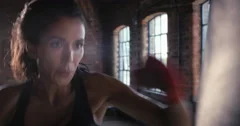 Kickboxing woman training punching bag in fitness studio