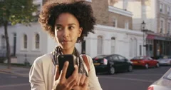 Beautiful Mixed race woman using smart phone technology app walking through city