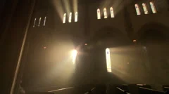 Priest walking down the aisle in darkened nave of Catholic church