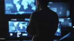 Male IT employee is looking at computer screens with maps and data on display