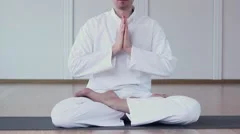 A Man Dressed in White Practices Yoga. He Folded his arms and namaste