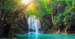 Sunshine and beautiful waterfall flows to wild pond in rain forest of Thailand
