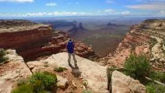 Aerial drone filming of hiker hiking to cliff edge to reveal desert grand view