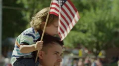 Medium slow motion shot of boy waving American flag at parade