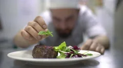 Chef is finishing meal teasty beef steak with salad for guest of restaurant