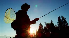 Sunrise silhouette of fisherman fly fishing outdoor in freshwater river