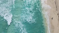 Overhead Aerial View of Couple Walking on Beach with Waves Breaking on the Sand