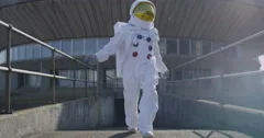 4K Funny astronaut doing a dance as he walks away from mission control building.