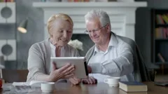 Happy lovely retired couple use tablet computer and laugh