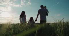 young happy Asian family goes on a green field with two children, slow motion